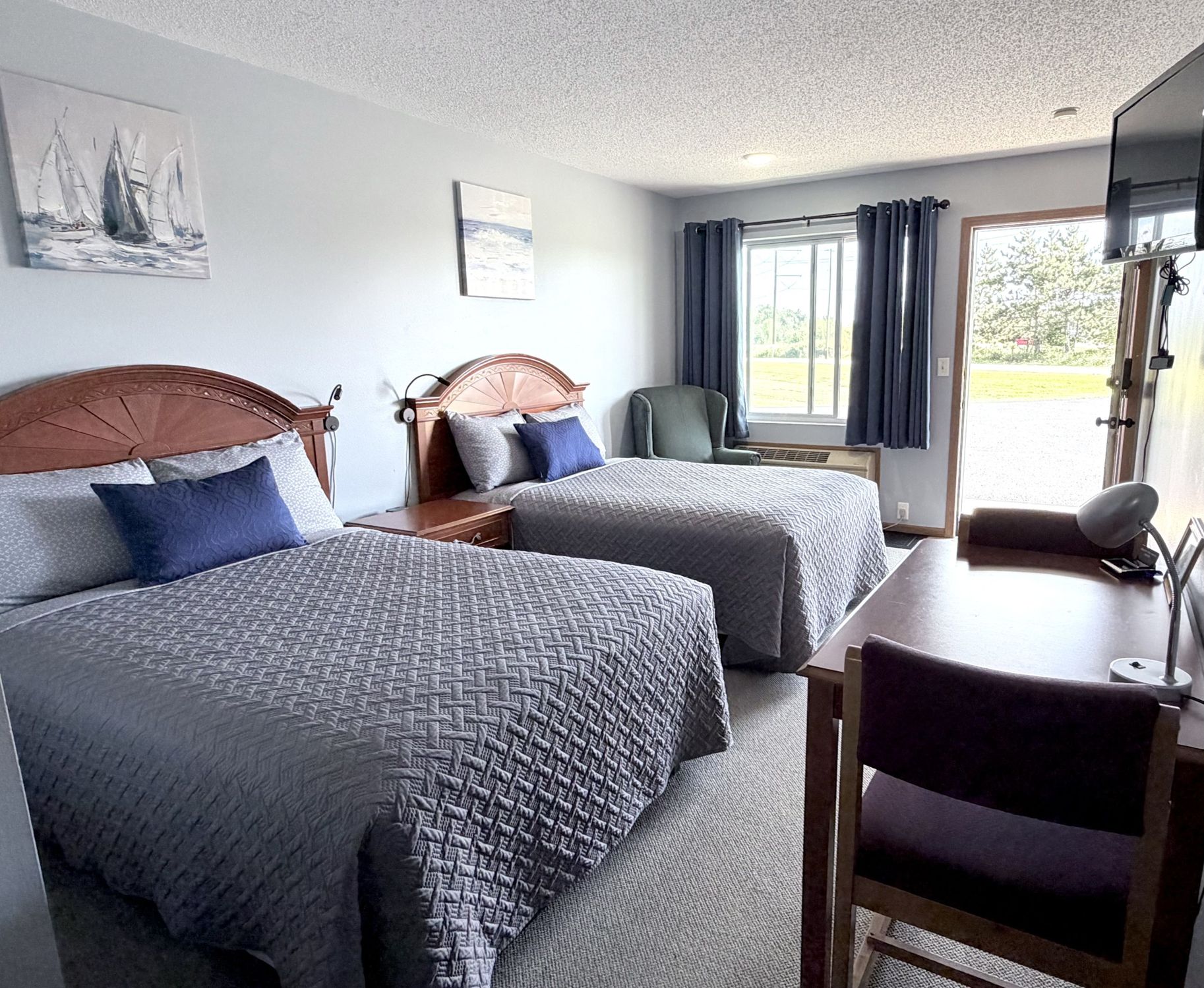 Double room with two beds, armchair, and a window overlooking the grounds