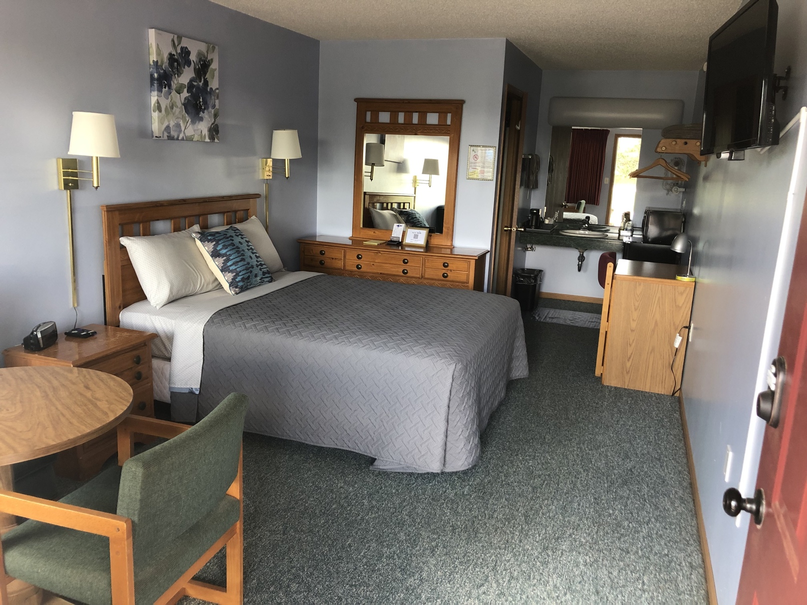 Queen room with a queen bed, dresser, table, and vanity area